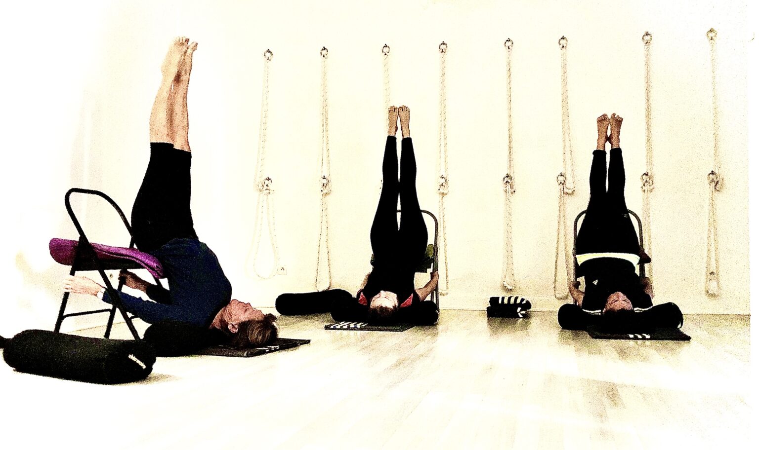 Trois &eacute;l&egrave;ves en posture invers&eacute;e soutenue par des chaises, pendant un cours